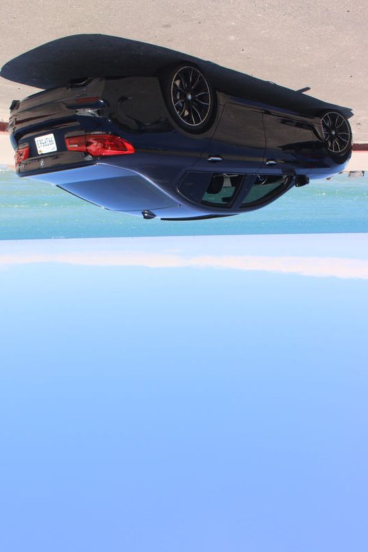 BMW 540i parked by the ocean with waves in the background